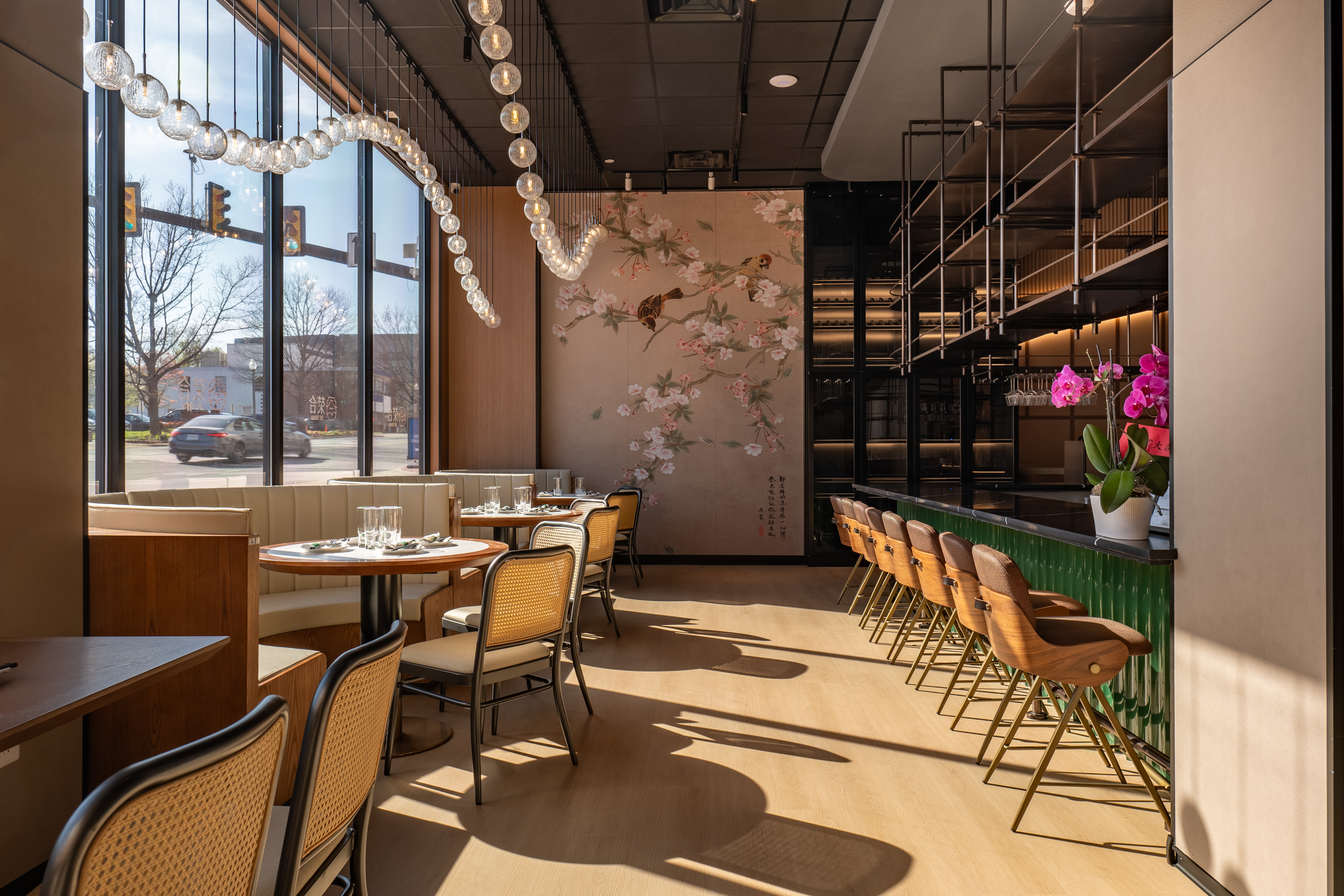 Tamu restaurant interior with seating area, green bar, and cherry blossom wall art